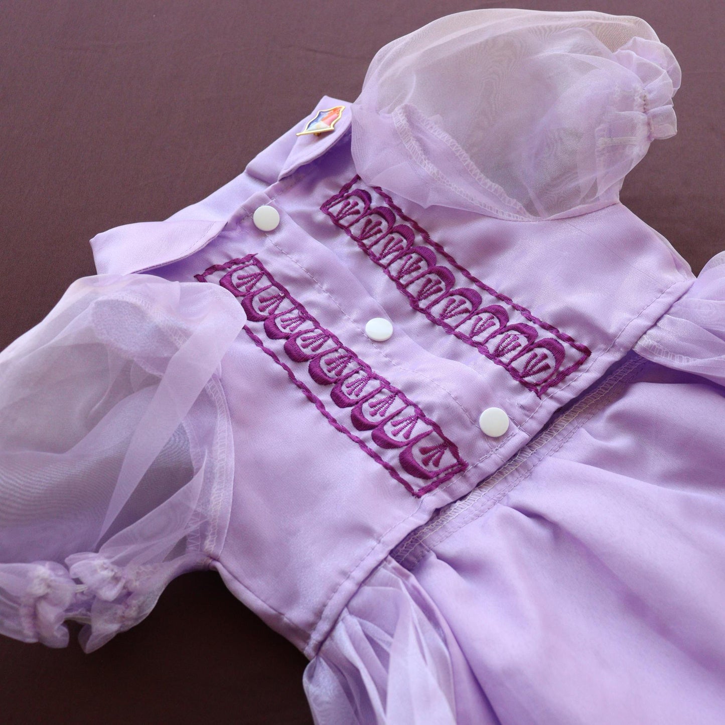 Close-up of a purple dress with white lace details on a brown background